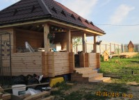 Беседка из бруса под коричневой кровлей со снегоудержателями