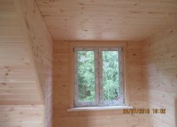 Пластиковое окно в комнате обитой вагонкой на втором этаже брусового дома